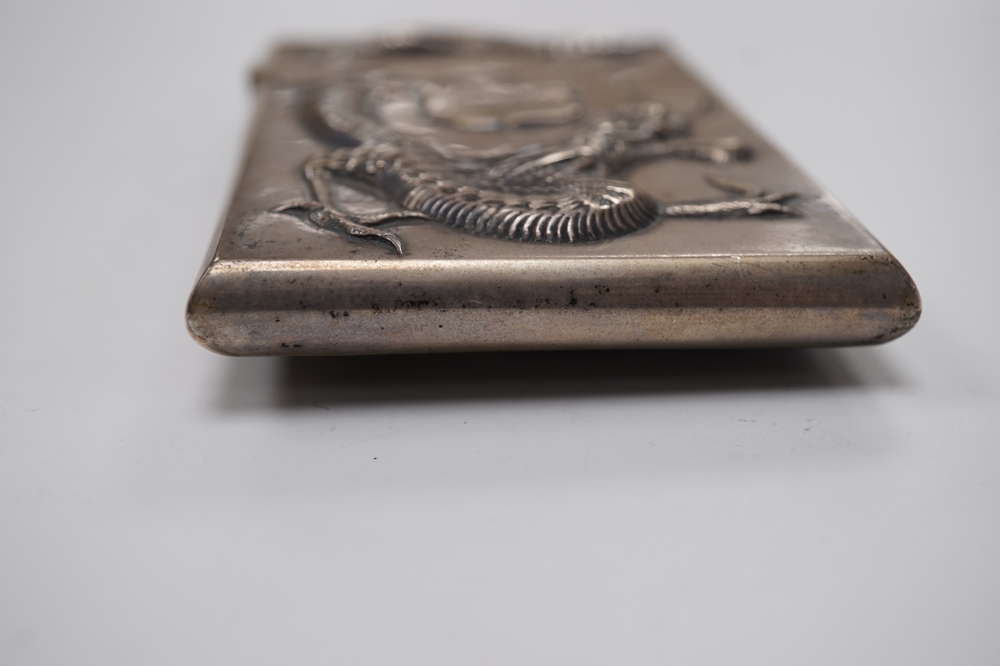 A late 19th century Chinese Export white metal card case, by Cum Shing, Canton, embossed with a dragon and applied shield shaped panel engraved with monogram, 90mm, 85 grams.